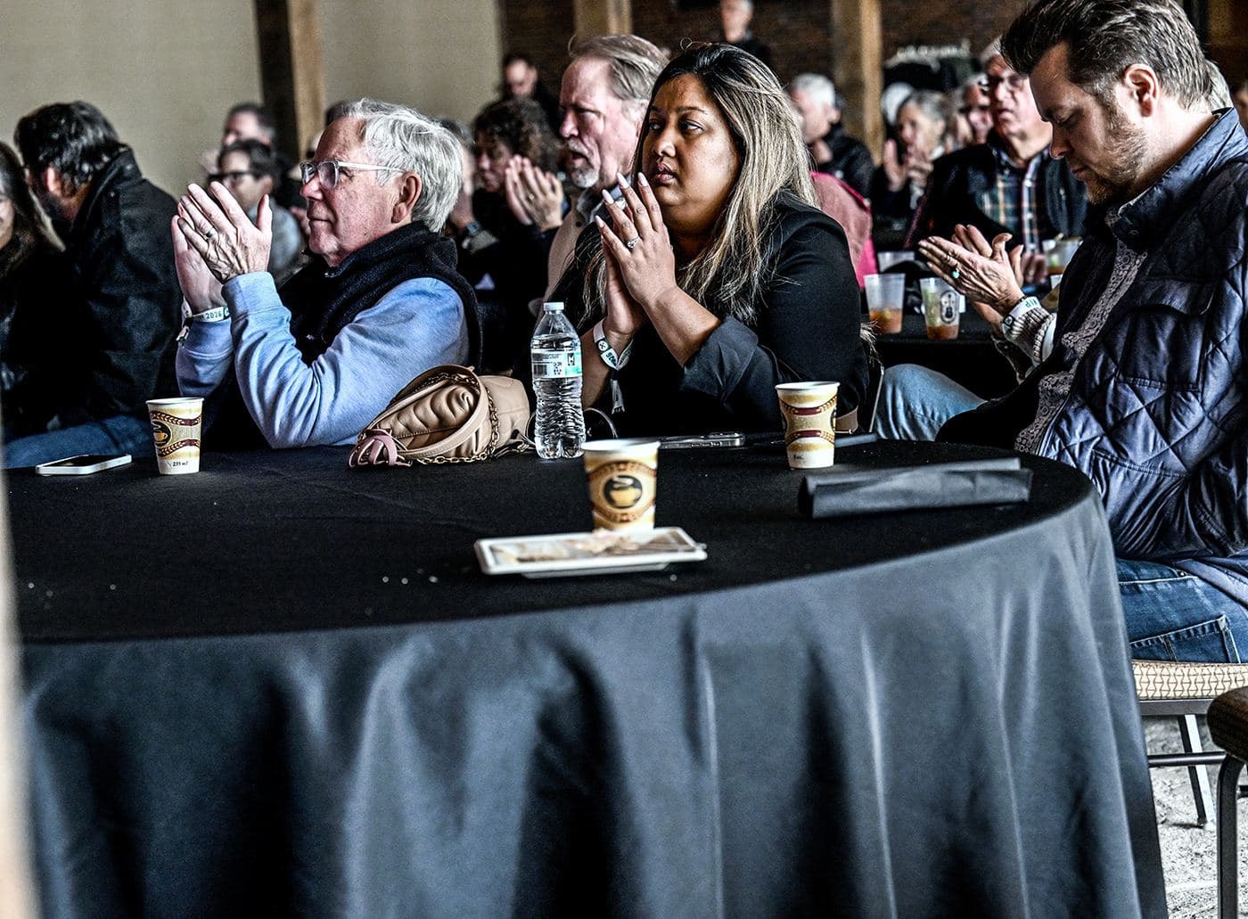 Guests at round tables with coffee applauding a Sunday morning set