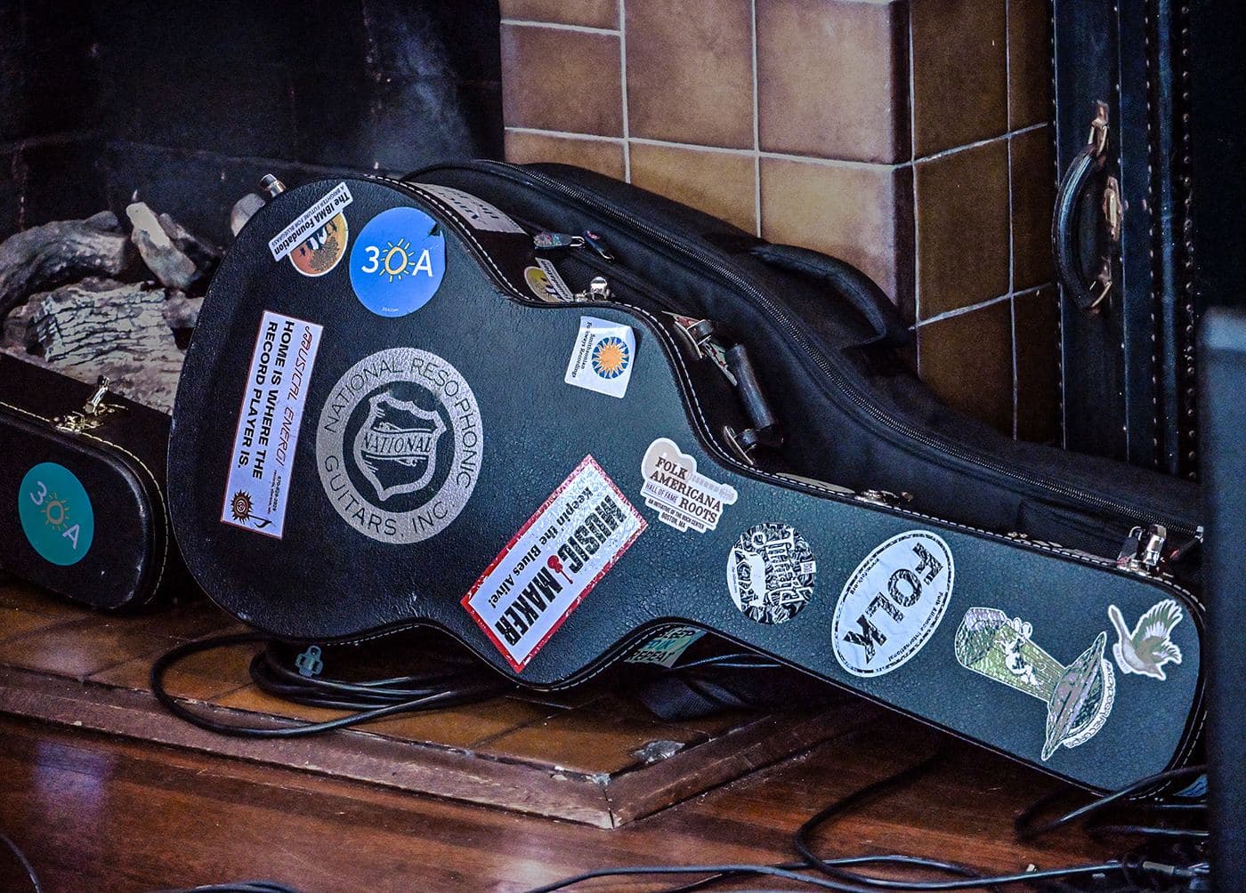 A guitar case covered in festival stickers leaning against a wall backstage