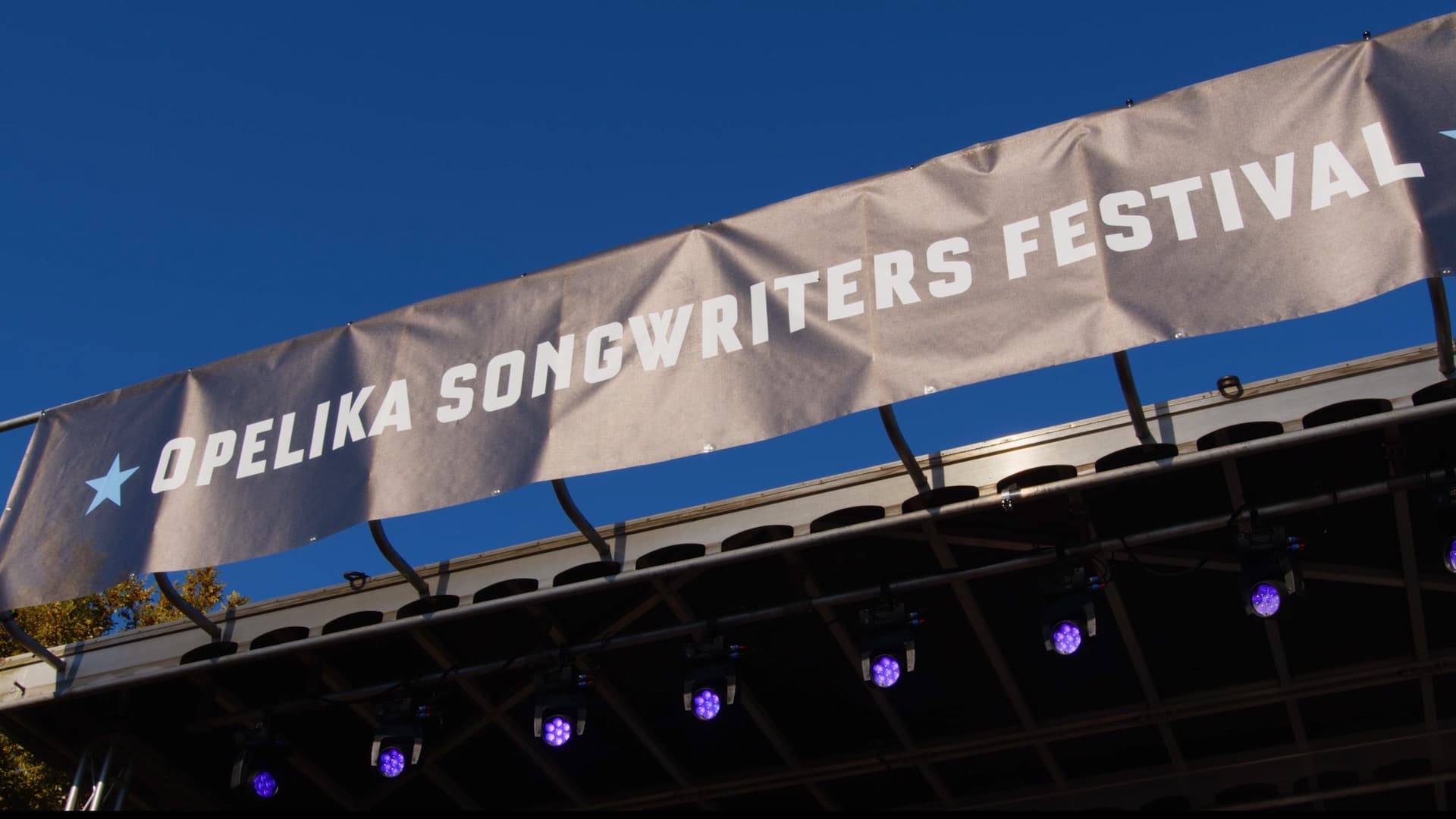 The Opelika Songwriters Festival banner above the outdoor stage